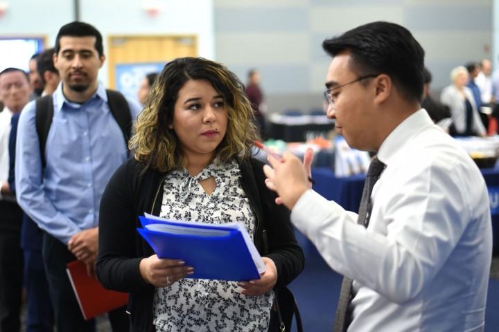 Student holding a portfolio speaks with employer at the career fair. 
